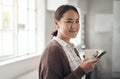 Downtime enjoyed as a homebody. a young woman using a cellphone while drinking coffee in the kitchen at home.