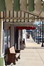 Downtown sidewalk with awnings, bench, barber pole, and street lamp post lights