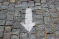 A downwards arrow painted with white paint on the old stoneblock pavement cobbled with square granite blocks Royalty Free Stock Photo