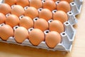 A dozen brown eggs in a carton on a wooden table Royalty Free Stock Photo