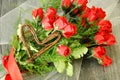 Dozen red roses, with green, red ribbon, wicker heart Royalty Free Stock Photo