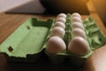 Dozen white fresh chicken eggs in the green cardboard egg tray on wooden table background. Fresh organic eggs in Royalty Free Stock Photo