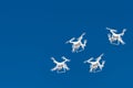 Dozens of drones swarm in the blue sky. Quadcopters drones with digital camera in the air over city. New technology in the aero