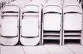 Dozens of fold up white metal chairs stacked .outdoor Party Royalty Free Stock Photo