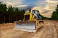 Dozer during clearing forest for construction new road. Bulldozer at forestry work on sunset background. Earth-moving equipment at Royalty Free Stock Photo