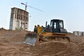 Dozer on earthmoving at construction site. Bulldozer on road work. Construction machinery and equipment on groundwork. Tower