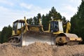 Dozer and Vibro Roller Soil Compactor at road construction and bridge projects in forest area. Heavy machinery for road work.