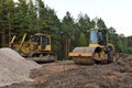 Dozer and Vibro Roller Soil Compactor at road construction and bridge projects in forest area. Heavy machinery for road work.