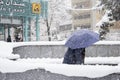 Women comes out from metro station with umbrella in snowy day