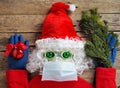 Draft of a comic image of a frightened Santa Claus in a hat made of a medical mask, gloves, glasses on a wooden background. Use