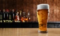 Draft or craft beer in tall clear glass. With cold steam, White beer foam placed on a wooden floor, behind the background is a Royalty Free Stock Photo