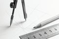 Drafting compass, ruler, and pencil on a white surface with grid lines, indicating technical drawing Royalty Free Stock Photo