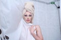 Drag queen person behind the shower curtain with a towel around the head.