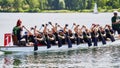 Dragon boat with rowers dressed in black and a redhead drummer on a lake, collaboration concept Royalty Free Stock Photo