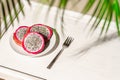 Dragon fruit, pitaya on a white wooden tray on the sand of tropical beach under a palm tree. Exotic food, snack. Summer travel. Royalty Free Stock Photo