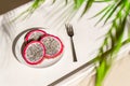 Dragon fruit, pitaya on a white wooden tray on the sand of tropical beach under a palm tree. Exotic food, snack. Summer travel. Royalty Free Stock Photo