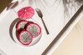Dragon fruit, pitaya on a white wooden tray on the sand of tropical beach under a palm tree. Exotic food with umbrella topical Royalty Free Stock Photo