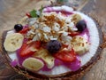 Dragon fruit smoothy in a natural traditional coconut fruit bowl on wooden table. Yogurt smoothie on coconut bowl.