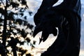 Medieval dragon statue silhouette with mediterranean sunset in background. Dragon silhouette closeup in public place.