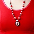 Dragon red eye cabochon and ceramic beads. necklace on a young girl on a red background