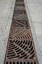 Drain of metal grate around with rough beton road Royalty Free Stock Photo