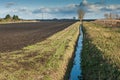Drainage channel running alongside a ploughed field
