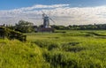 Drainage channels in the foreground of a view of the village of Cley and drainage channels in the marshes in Norfolk, UK