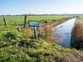 Drainage ditch and open gate leading on to meadow in polder Eempolder, Netherlands