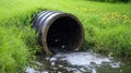 A drainage pipe surrounded by grass, with water flowing out, representing effective water management Royalty Free Stock Photo