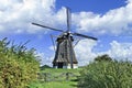 Drainage windmill with thatched roofing in a polder with dramatic shaped clouds and blue sky, Netherlands