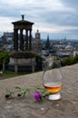 Dram glass of single malt scotch whisky and view from Calton hill to park and old parts of Edinburgh city in rainy day, Scotland, Royalty Free Stock Photo