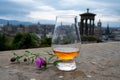 Dram glass of single malt scotch whisky and view from Calton hill to park and old parts of Edinburgh city in rainy day, Scotland, Royalty Free Stock Photo
