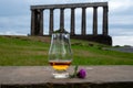 Dram glass of single malt scotch whisky and view from Calton hill to park and old parts of Edinburgh city in rainy day, Scotland, Royalty Free Stock Photo