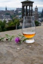 Dram glass of single malt scotch whisky and view from Calton hill to park and old parts of Edinburgh city in rainy day, Scotland,