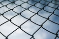 Dramatic Blue Sky With White Clouds Through A Metal Grid Chain Fence . Low Angle View