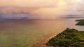 Dramatic aerial photo of rain clouds over ocean. Black clouds with rain over sea surface and coast Royalty Free Stock Photo