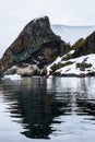 Dramatic Antarctic snow covered and rocky shoreline in Paradise Harbor, Antarctica, with small inflatable rafts cruising in foregr Royalty Free Stock Photo