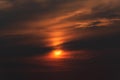 Dramatic apocalyptic scene of bright orange sun behind sinister dark clouds