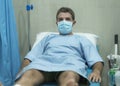 Dramatic artistic hospital portrait of attractive and scared man infected by covid19 - adult male in face mask receiving