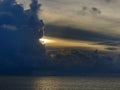 Sun burst through dark towering clouds.