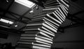 Towering stack of books reaching towards a skylight in a dramatic black and white photograph Royalty Free Stock Photo