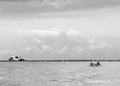 Dramatic black and white image of man floating in a caribbean bay with a shipwreck boat in background.