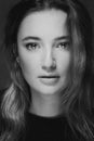 Dramatic black and white portrait of a beautiful lonely girl with freckles isolated on a dark background in studio shot Royalty Free Stock Photo