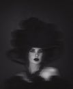 A dramatic black and white portrait of a mysterious woman with dark makeup, lush curly hair, and a sultry gaze against a shadowy