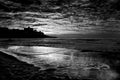 Dramatic black and white sea landscape image with dark sky and white waves. City in background. Fine art seascape