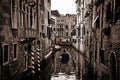 Dramatic black and white view of the small canals in Venice with classic buildings and a traditional boat on the water