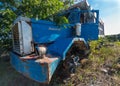 Dramatic blue image of a old abandoned rusty truck in an overgrown field in the caribbean.