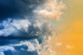 Dramatic blue thunderclouds on left, stunning yellow-golden fluffy clouds illuminated by rays of sun on right Royalty Free Stock Photo