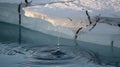 Dramatic close-up of melting ice, showcasing water droplets falling into a calm pool. Royalty Free Stock Photo