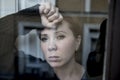 Dramatic close up portrait of young beautiful woman thinking and feeling sad suffering depression at home window looking depresse Royalty Free Stock Photo